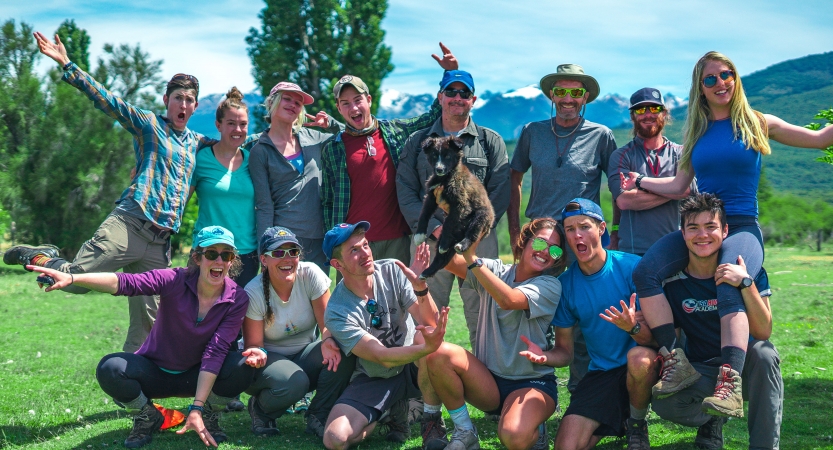 A group of people pose for a photo in front of mountains. 